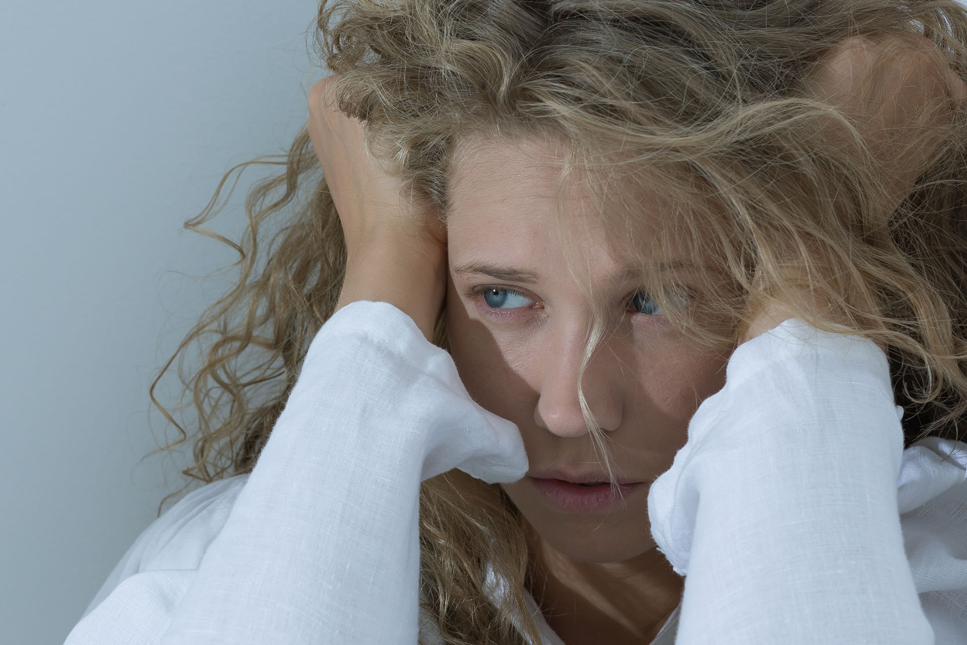 lęki Smutna, wystraszona kobieta w białej koszuli, trzymająca się za włosy